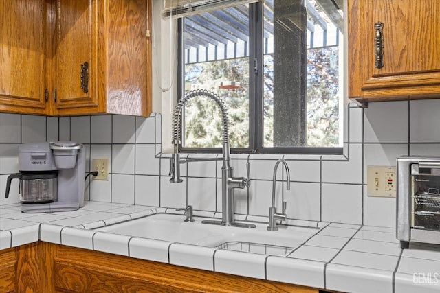 kitchen with tasteful backsplash, brown cabinetry, and a wealth of natural light