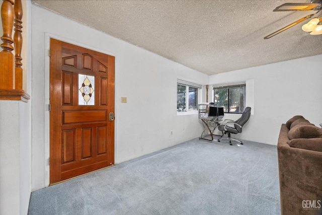 carpeted foyer entrance with ceiling fan and a textured ceiling