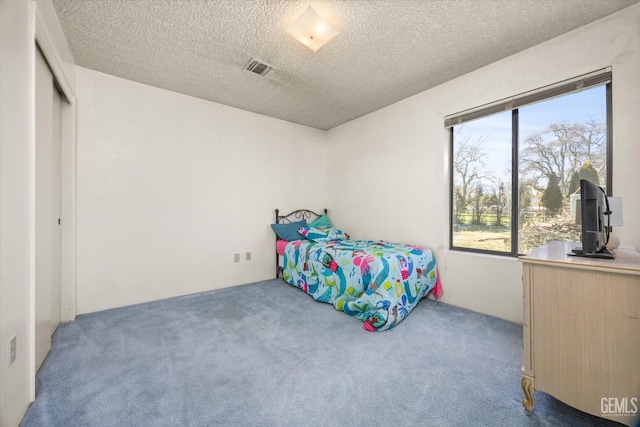 carpeted bedroom featuring visible vents and a textured ceiling