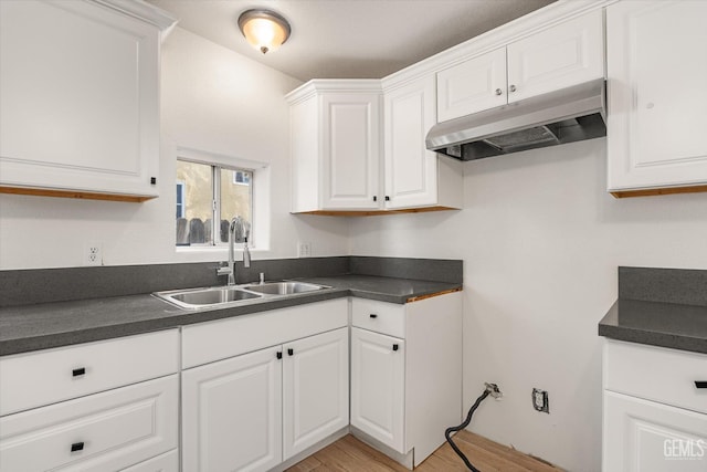 914 P St, Bakersfield, CA 93304 - kitchen featuring under cabinet range hood, dark countertops, white cabinetry, and light wood-style floors