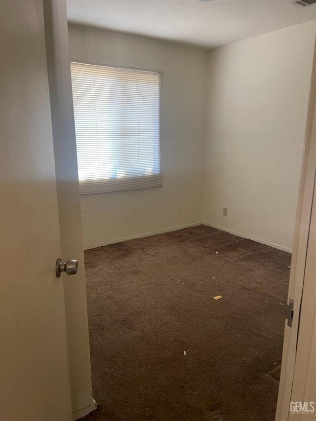 unfurnished room featuring dark colored carpet