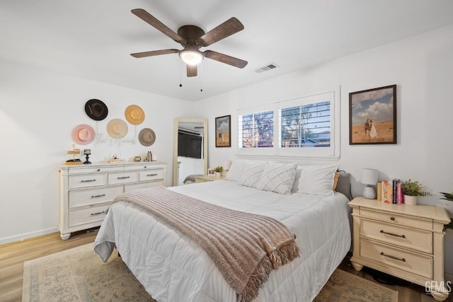 bedroom featuring baseboards, visible vents, ceiling fan, and wood finished floors