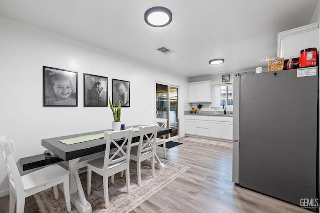 dining space with light wood-style floors and visible vents