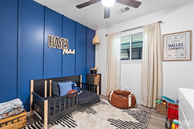 bedroom with a ceiling fan, visible vents, and wood finished floors