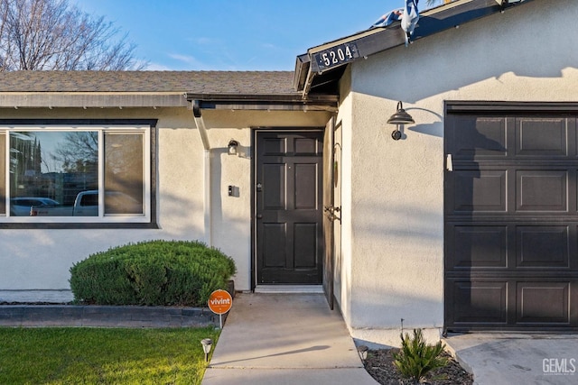 entrance to property featuring a garage and stucco siding