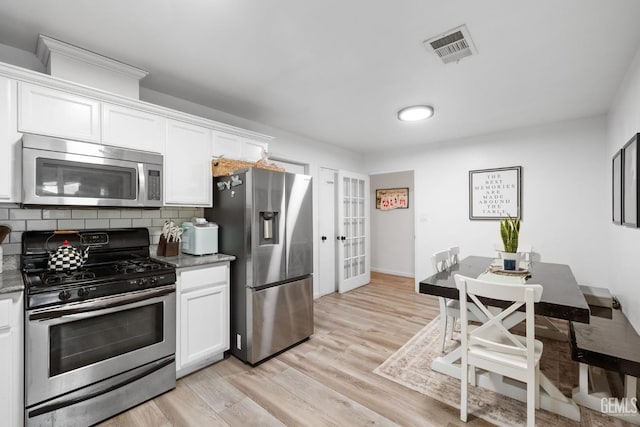 kitchen with stainless steel appliances, backsplash, visible vents, and white cabinets