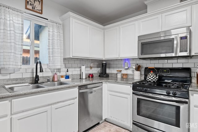 kitchen featuring stainless steel appliances, a sink, white cabinetry, light countertops, and decorative backsplash