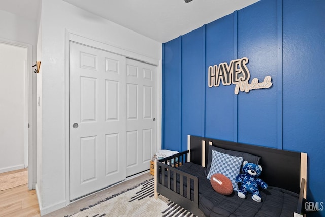 bedroom featuring a closet, wood finished floors, and a decorative wall