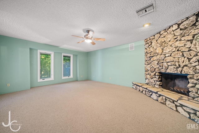 unfurnished living room with carpet, a fireplace, visible vents, and a ceiling fan