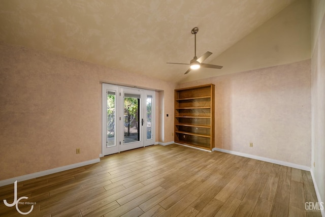 spare room with light wood finished floors, baseboards, vaulted ceiling, and a ceiling fan