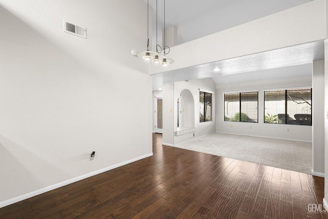 empty room with lofted ceiling, a notable chandelier, and dark hardwood / wood-style flooring