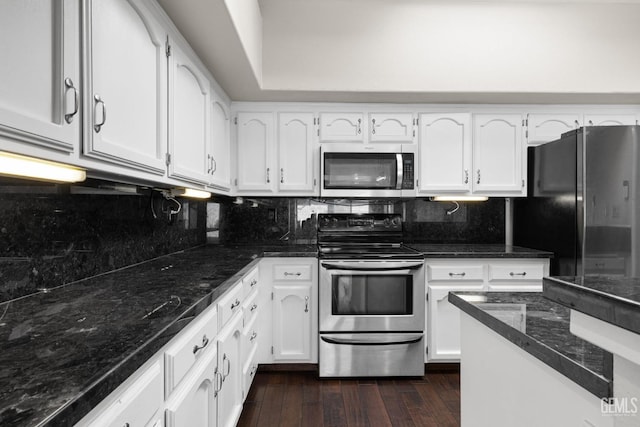 kitchen featuring dark wood-type flooring, white cabinetry, backsplash, dark stone countertops, and stainless steel appliances