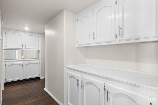 bar featuring dark wood-type flooring and white cabinets