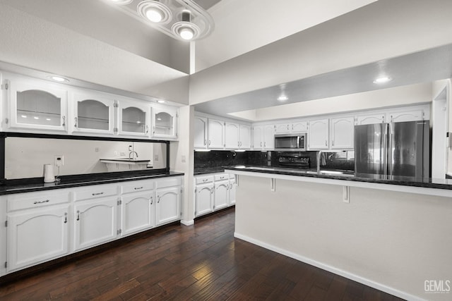 kitchen with dark wood-type flooring, refrigerator, tasteful backsplash, and white cabinets