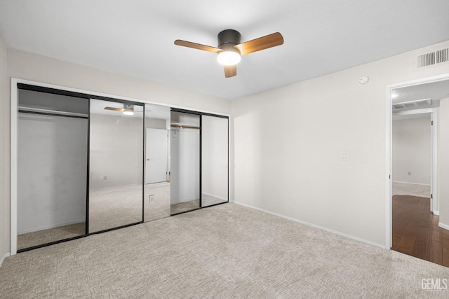 unfurnished bedroom featuring multiple closets, light carpet, and ceiling fan