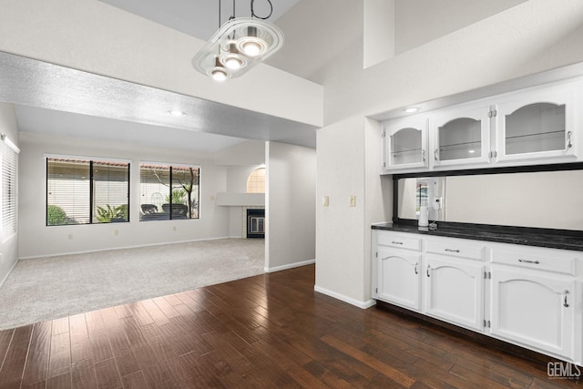 kitchen with hanging light fixtures, high vaulted ceiling, white cabinets, and dark hardwood / wood-style flooring