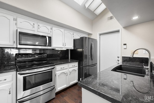 kitchen featuring vaulted ceiling, white cabinetry, sink, decorative backsplash, and stainless steel appliances