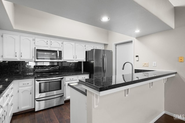 kitchen featuring white cabinetry, appliances with stainless steel finishes, a breakfast bar, and kitchen peninsula