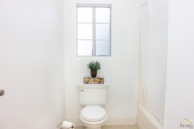 bathroom featuring shower / tub combo, toilet, and a healthy amount of sunlight