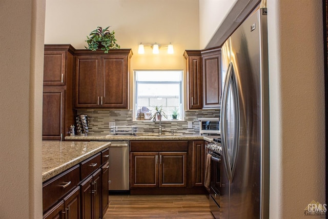 kitchen with decorative backsplash, appliances with stainless steel finishes, light stone counters, and sink