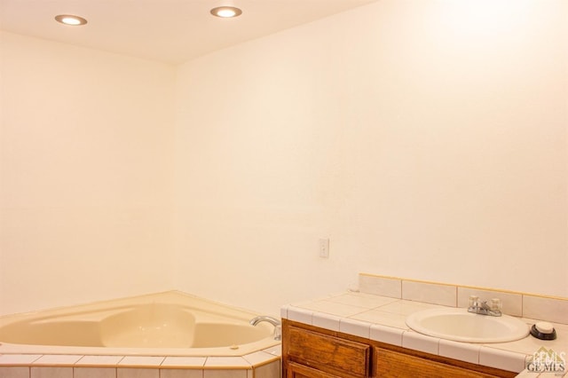 bathroom featuring tiled bath and vanity