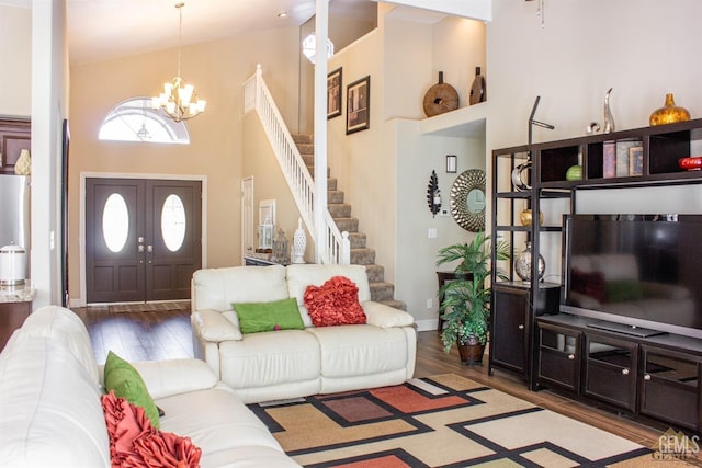 living room with hardwood / wood-style floors, a notable chandelier, and a towering ceiling