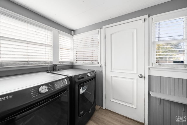 laundry room with washing machine and dryer and light hardwood / wood-style flooring