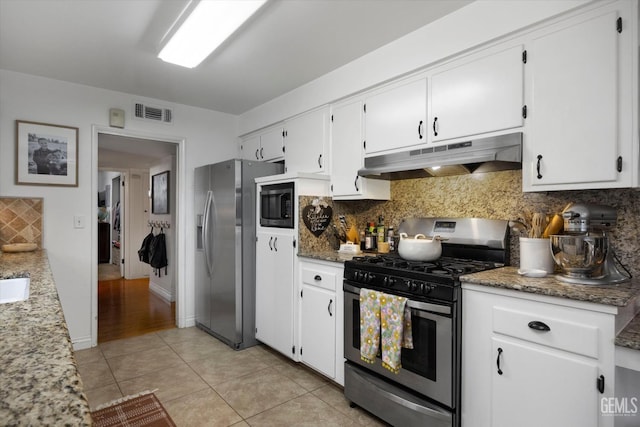 kitchen with white cabinets, visible vents, backsplash, under cabinet range hood, and appliances with stainless steel finishes