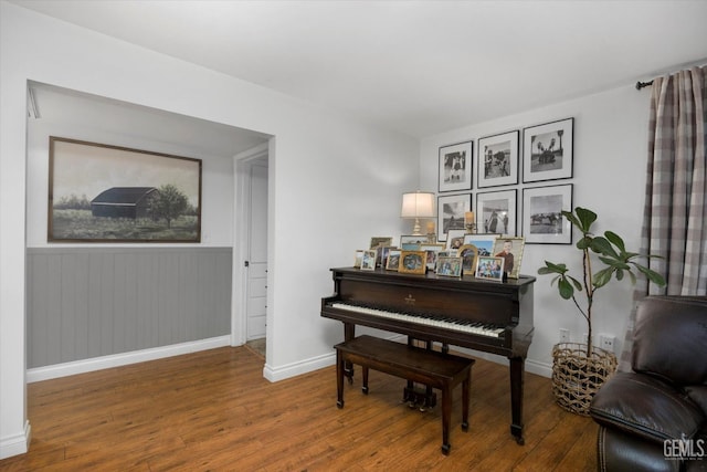 living area featuring baseboards, a wainscoted wall, and wood finished floors