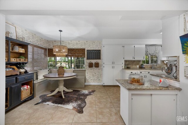 kitchen featuring plenty of natural light, an inviting chandelier, white cabinetry, and light tile patterned flooring