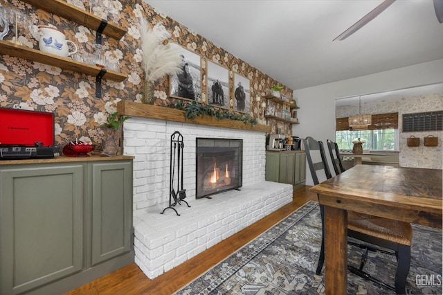 living room with wallpapered walls, wood finished floors, and a fireplace