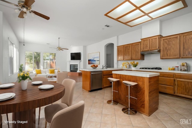 kitchen with stainless steel appliances, a center island, kitchen peninsula, and light tile patterned floors