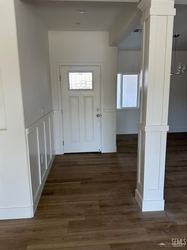 interior space with baseboards, decorative columns, visible vents, and dark wood-style flooring