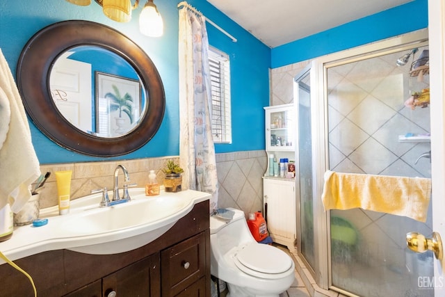 bathroom with tile walls, vanity, a shower with door, and toilet