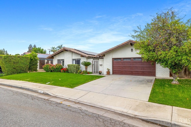 3406 Elm St, Bakersfield, CA 93301 - ranch-style home with roof mounted solar panels, concrete driveway, an attached garage, brick siding, and a front yard