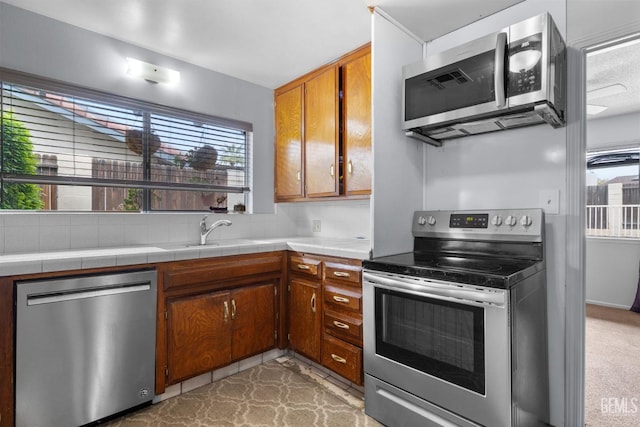 3406 Elm St, Bakersfield, CA 93301 - kitchen featuring tile counters, brown cabinetry, stainless steel appliances, and a sink
