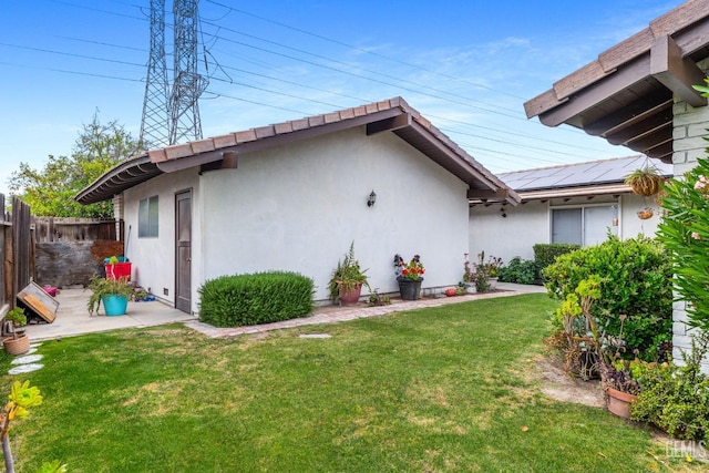 3406 Elm St, Bakersfield, CA 93301 - rear view of property with stucco siding, solar panels, fence, and a yard