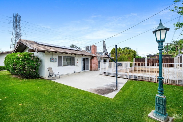 3406 Elm St, Bakersfield, CA 93301 - rear view of property with roof mounted solar panels, a fenced backyard, stucco siding, a patio area, and a lawn