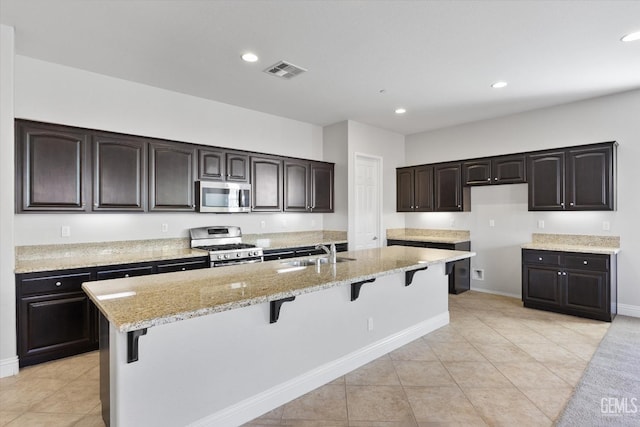 kitchen featuring sink, a kitchen breakfast bar, stainless steel appliances, and dark brown cabinets