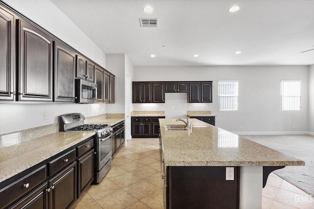 kitchen with sink, dark brown cabinetry, a center island with sink, and stainless steel appliances