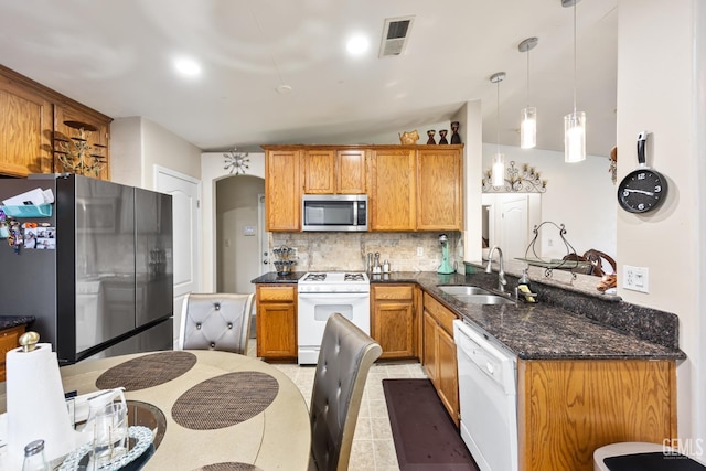 kitchen featuring dark stone countertops, appliances with stainless steel finishes, sink, backsplash, and pendant lighting