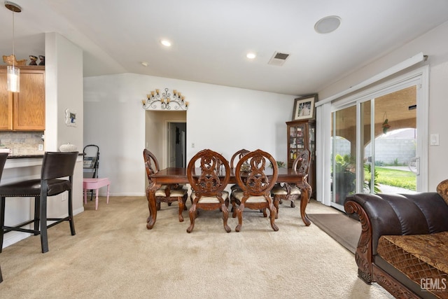 carpeted dining area with lofted ceiling