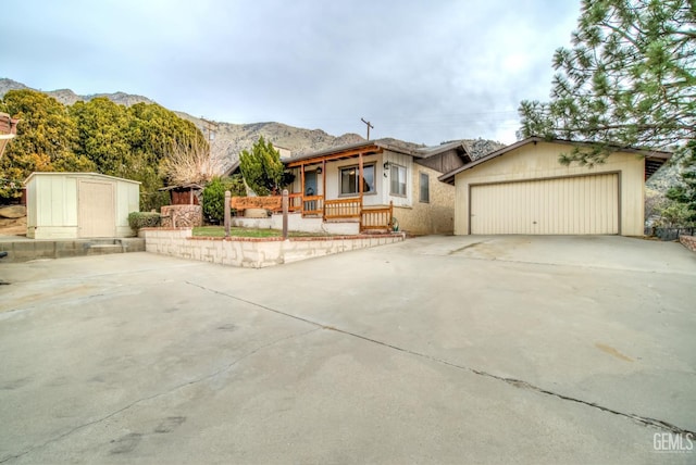 view of front of home with a garage, a mountain view, a porch, and a storage unit