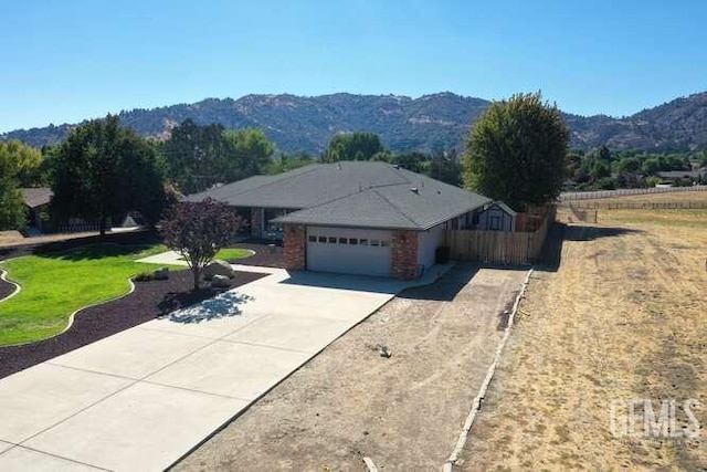 ranch-style home with a mountain view, a garage, and a front lawn