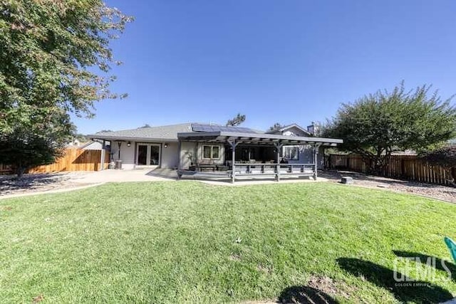 rear view of property with a lawn, solar panels, and a patio area