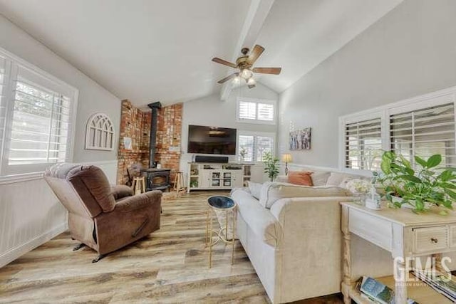 living room featuring light hardwood / wood-style floors, plenty of natural light, ceiling fan, and a wood stove