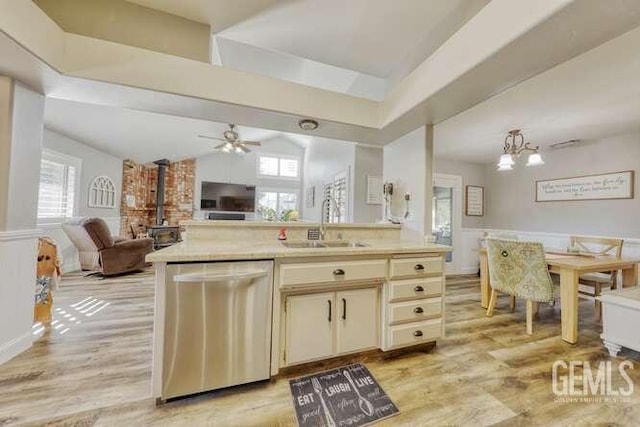 kitchen with a wood stove, sink, stainless steel dishwasher, cream cabinets, and ceiling fan with notable chandelier