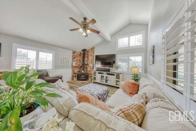 living room with a wood stove, ceiling fan, beamed ceiling, and high vaulted ceiling