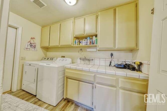 laundry room with cabinets, independent washer and dryer, light hardwood / wood-style floors, and sink