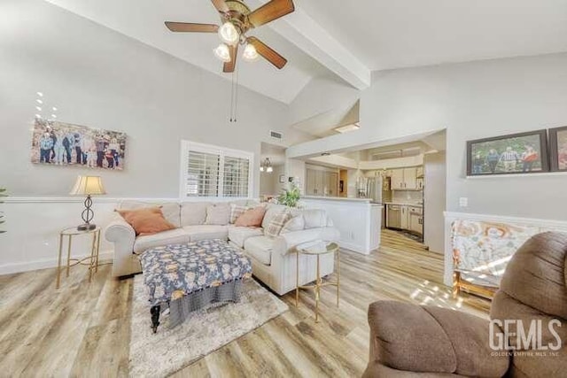 living room with ceiling fan, lofted ceiling with beams, and light hardwood / wood-style floors